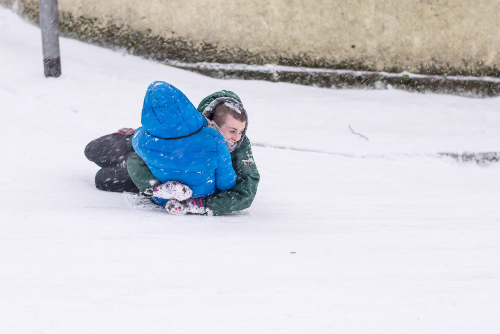 Students use each other as sledges in snow