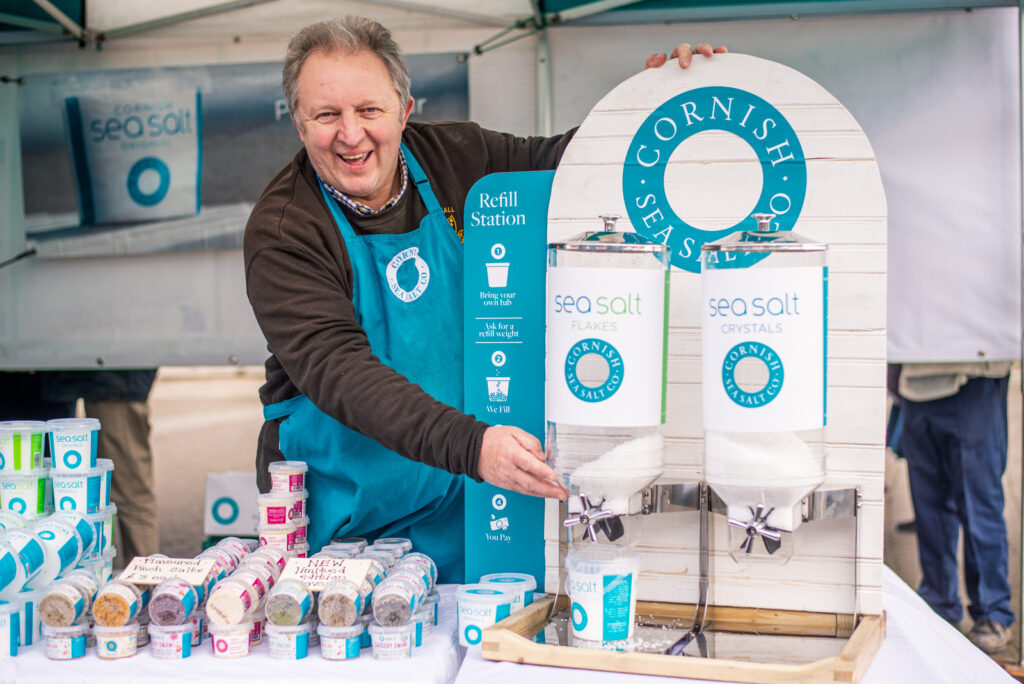 Man behind stall selling Cornish Sea Salt products. Promotional photography by Claire Wilson.